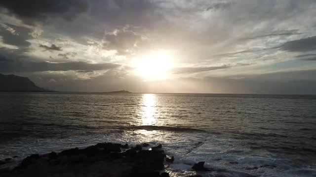 Drone flying on the rocky shore of capo Gallo and filming a sunset above Isola delle Femmine, Palermo province, Sicily, Italy