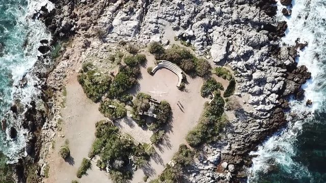 overhead drone zoom in on anfiteatro Barcarello near Sferracavallo village, Palermo province, Sicily, Italy, surrounded by waves dashing on the rocky shores