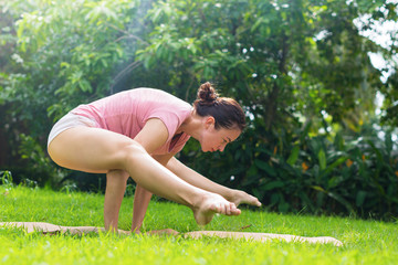 Naklejka na ściany i meble Girl doing yoga on open air on natural meadow