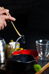 The process of making blue matches. Pounded tea poured into a bowl. Healthy food cocnept. Traditional Asian drink. Dark background. Vegetarian healthy drink, beverage, Matcha Tea ceremony