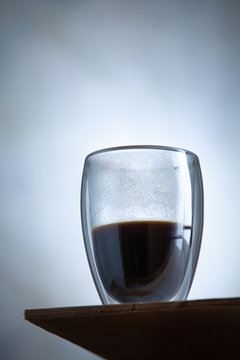 Close up view on hot glass of coffe stands in front of a concrete wall. Morning drink cocnept. Breakfast, Creaitive still life photo of food. trending double-walled glass. Cup of espresso coffee