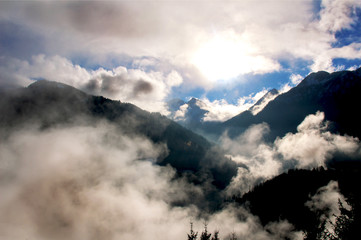 Clouds in front of the sun and blue sky in the Austrian Alps.