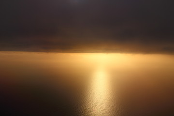evocative imagine of sunset over the sea from the plane with clouds in the background