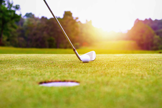 Golf balls and golf club on green grass shiny light sunse,