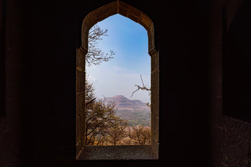 Landscape photo of beautiful nature with a tree & mountains from the window of a old fort