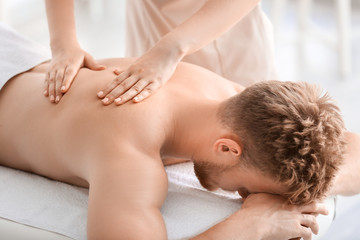 Fototapeta na wymiar Handsome young man receiving massage in spa salon