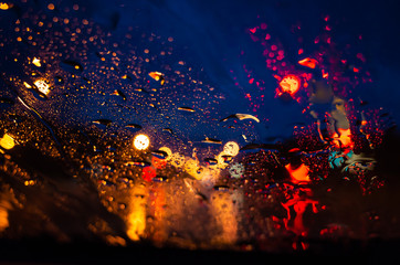 The bright lights of the night city through the glass in the drops of rain. Photo for background.