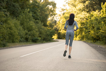 Fototapeta premium girl on a morning run. girl runs on the road. woman sport