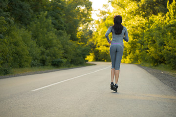 Obraz premium girl on a morning run. girl runs on the road. woman sport