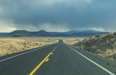 Road ahead with storm clouds above mountain in Oregon, USA