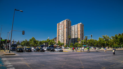 Obraz premium Samochody i ludzie przekraczają przejście dla pieszych w centrum Santiego w Chile.