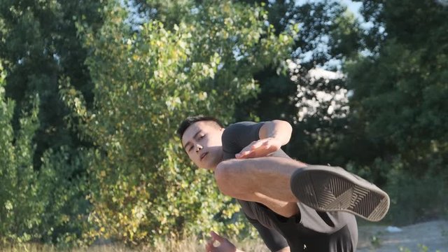 A young sportsman boxer and kickback training in the park. The young guy works out the technique of kicks