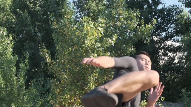 A young sportsman boxer and kickback training in the park. The young guy works out the technique of kicks
