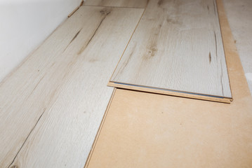 Laminate flooring in apartment. Maintenance repair works renovation. Restoration of wooden parquet planks indoors.