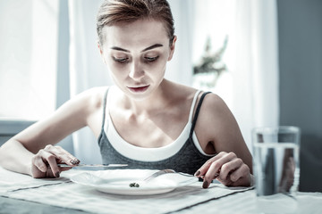 Attentive young female person staring at her plate