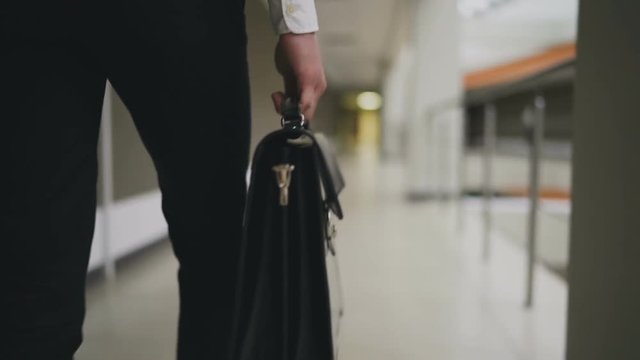 Businessman with briefcase walking across the office building. Slow motion 100 fps
