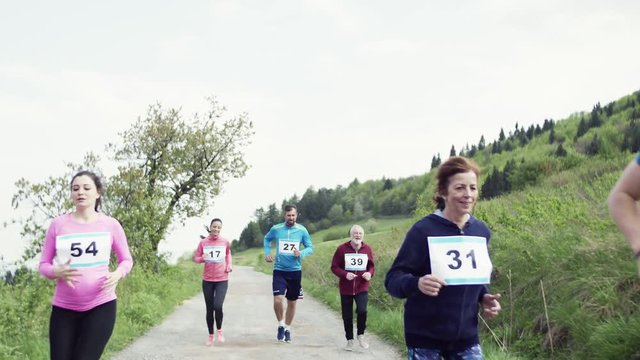 Large group of multi generation people running a race competition in nature.