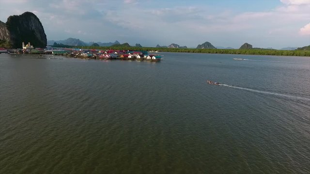 An establishing shot of boats sailing back to a settlement surrounded by water in Thailand