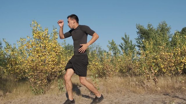 A young sportsman boxer and kickback training in the park. The young guy works out the technique of kicks