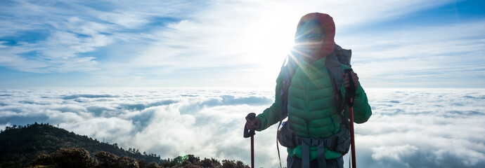 Successful young woman backpacker at sunrise mountain peak