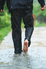 A man in the rain is barefoot in puddles