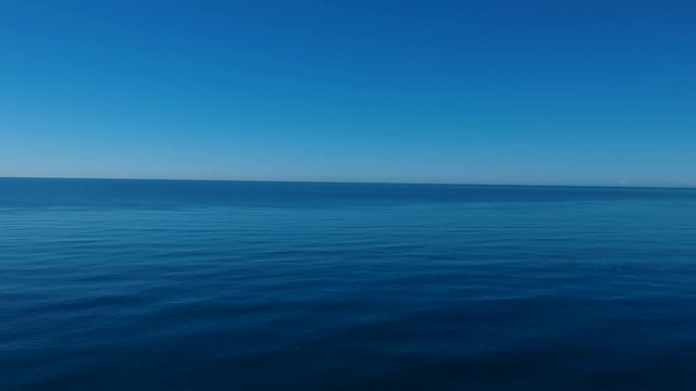Background of a tranquil calm ocean and windless blue sky