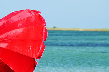 Red beach umbrella on the tropical beach. Relaxing summer background