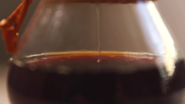 Dripping coffee into container looking at the bottom of a glass container when you see a stream of coffee dripping through a white natural filter on the bottom press capture in slow motion at 120 FPS.