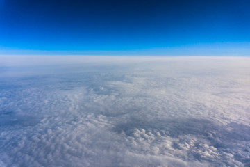 Fototapeta na wymiar Above clouds, view from pilot cabine airplane. Blue sky, white clouds with magic and soft sun light.