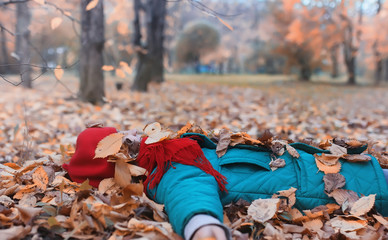 Obraz premium Girl in autumn city park in leaf fall. Young beautiful mother with her daughter on nature. A girl in a hat walks in the park.