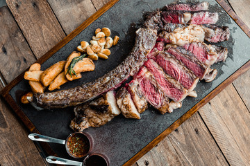 Grilled Australian tomahawk steak on black plate with potato and garlic fried