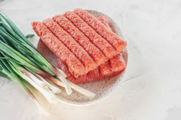 Chevapchichi is a national Balkan dish. Close up a row of fresh raw beef kebabs