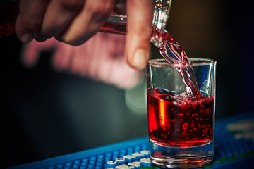 a red drink is poured into a glass