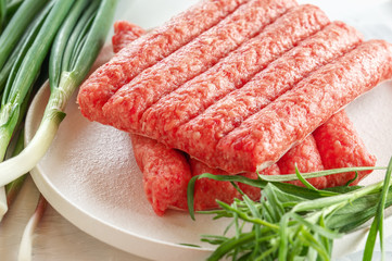 Chevapchichi is a national Balkan dish. Close up a row of fresh raw beef kebabs