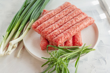 Chevapchichi is a national Balkan dish. Close up a row of fresh raw beef kebabs