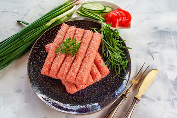 Chevapchichi is a national Balkan dish. Close up a row of fresh raw beef kebabs.