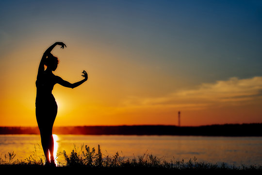 Ballerina dancing on the beach in the setting sun. silhouette image. copy space.