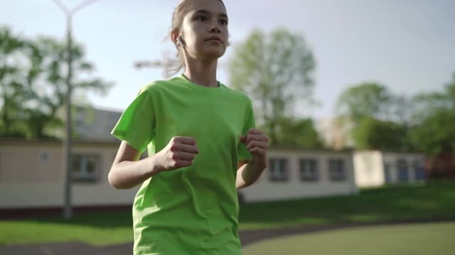 Child, teenager, 11 year old girl runs on his school's track. Slow motion