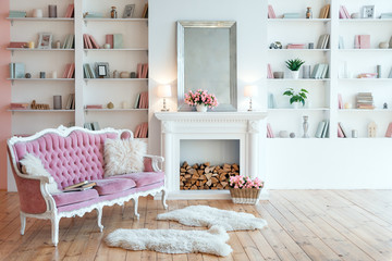 Fototapeta na wymiar Modern light interior with fireplace, spring flowers and cozy pink sofa