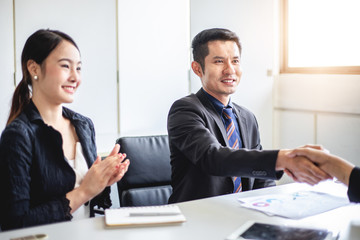 Business people shaking hands and smiling their agreement to sign contract and finishing up a meeting