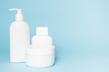 White jars of cosmetics on a blue background. Bath accessories. Face and body care concept