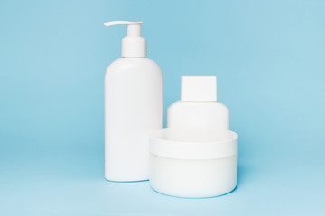 White jars of cosmetics on a blue background. Bath accessories. Face and body care concept