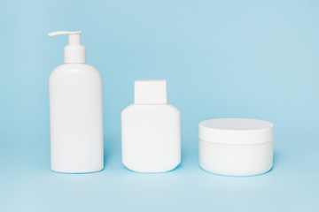 White jars of cosmetics on a blue background. Bath accessories. Face and body care concept