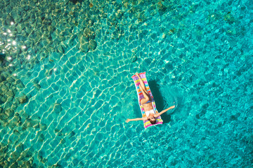 Turquoise ocean water and relaxed swimming woman, aerial drone shot.