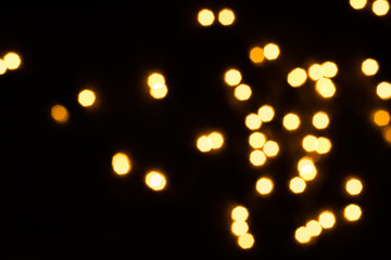 Golden bokeh lights scattered on black. Holiday concept