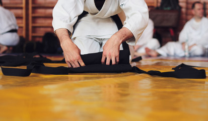 Color image of aikido. The male athlete carefully folds the black hackam. The traditional form of clothing in Aikido.