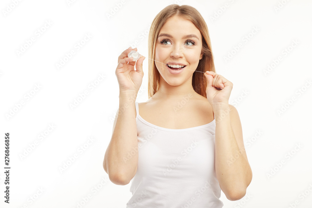 Wall mural smiling cute girl uses dental floss on a white background