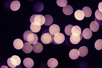 Violet bokeh lights glow on black. Holiday concept
