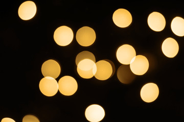 Black festive background with shining golden bokeh lights