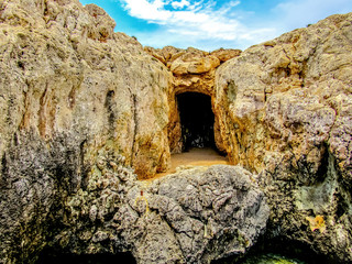 The entrance into a small dark sea cave along the rocky shore